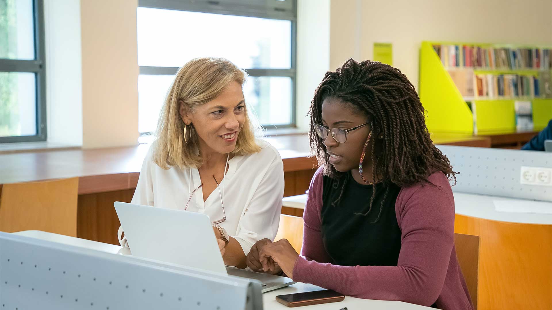 Two staff members talking over a laptop