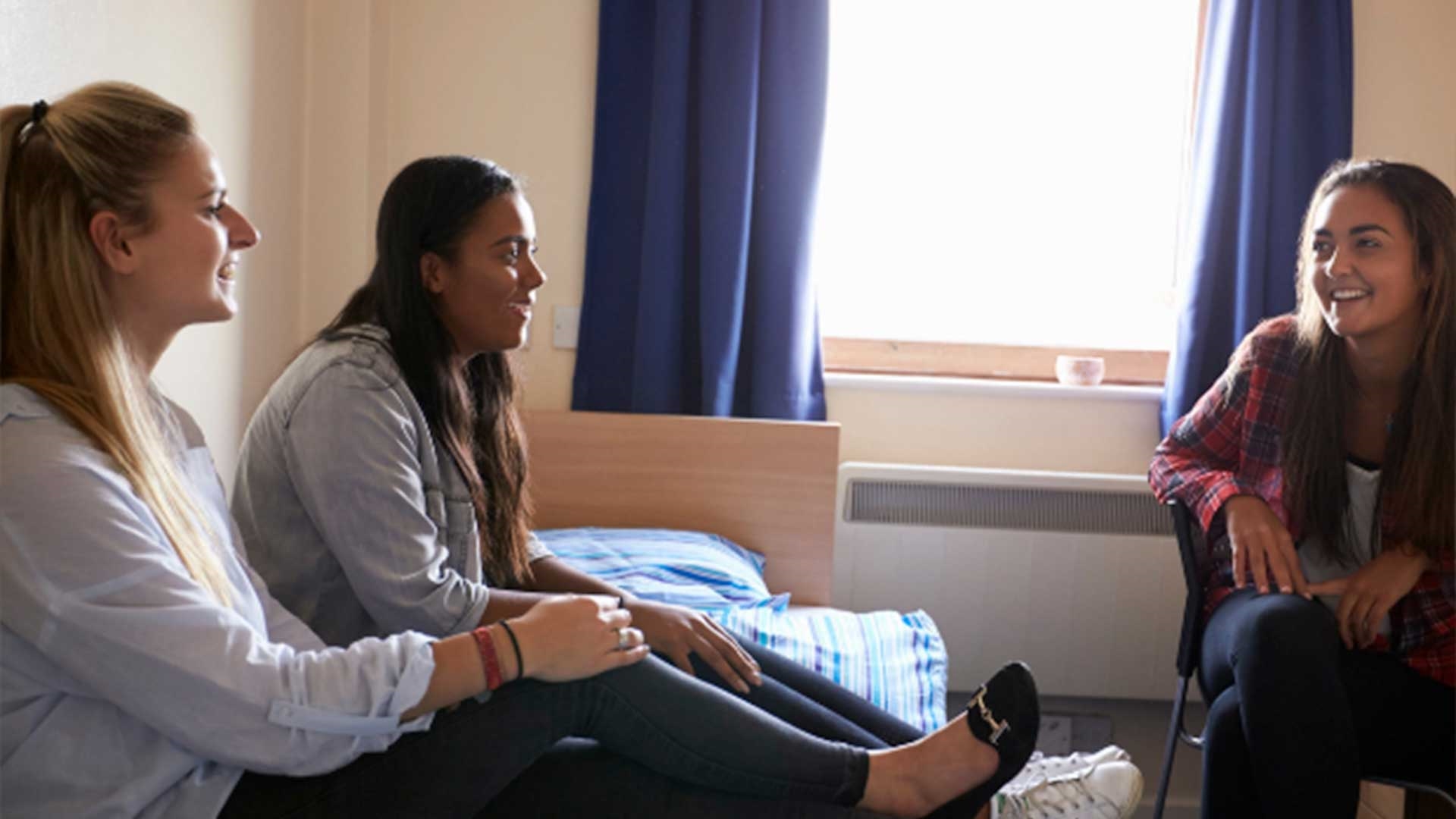 Three students sat in their university halls room talking