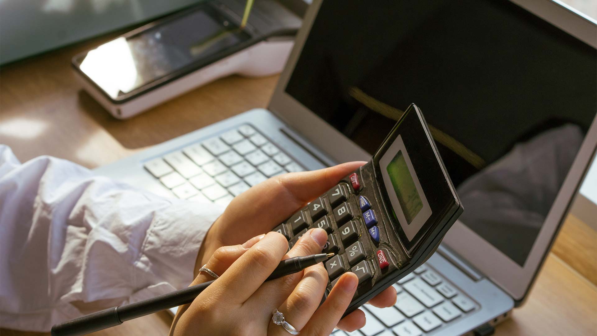 A person typing on a calculator