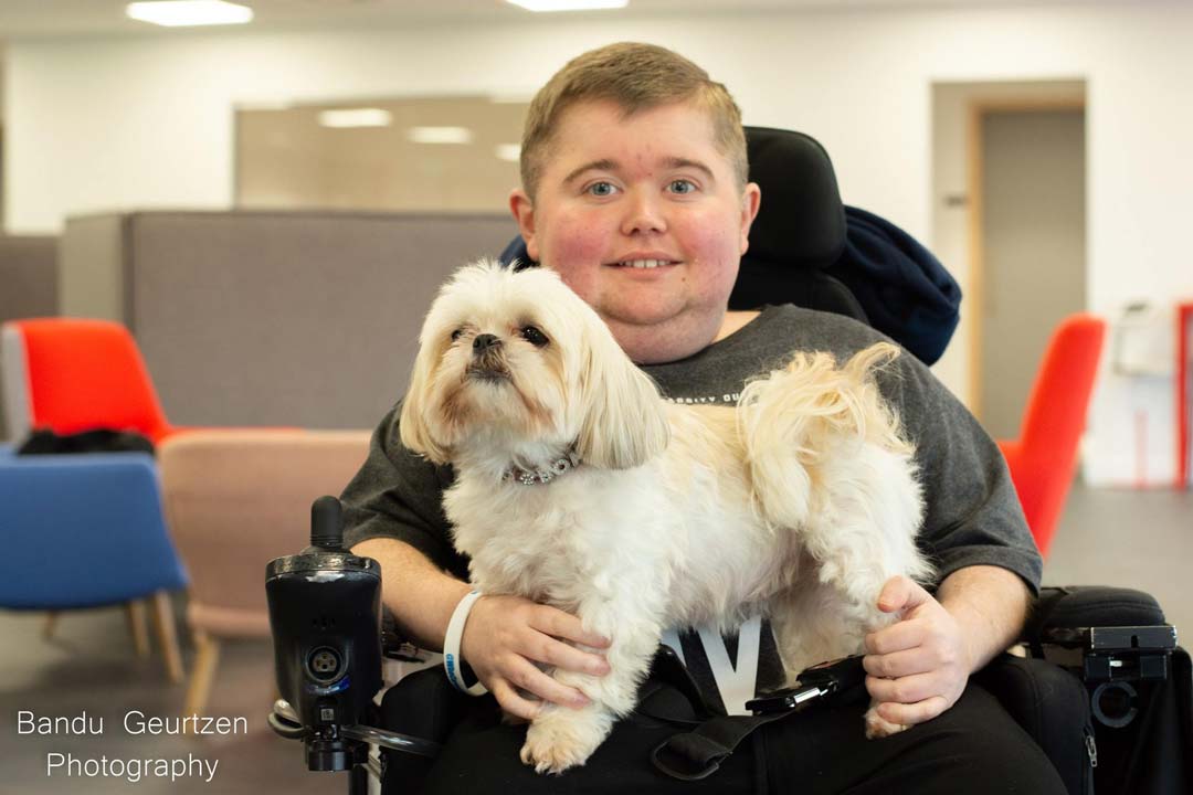 A student in a wheelchair with a white dog in their lap