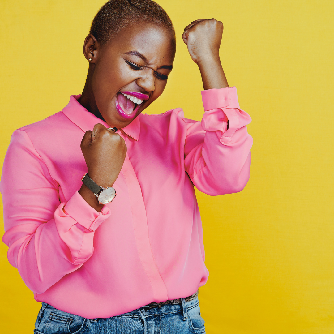 A black woman wearing a pink shirt celebrating