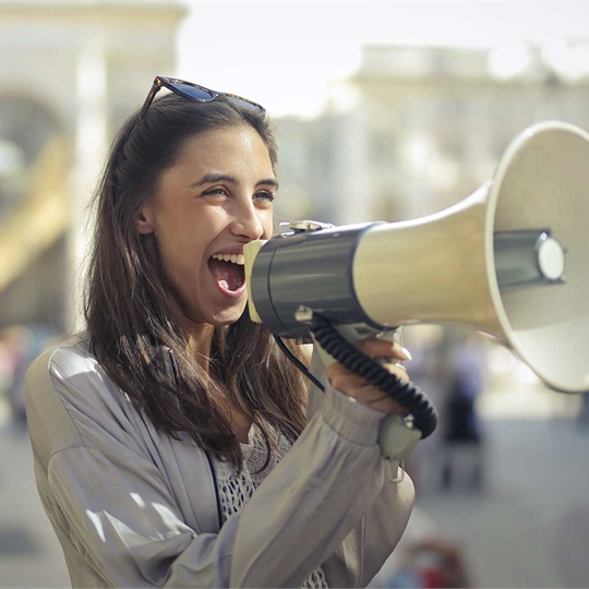 A student talking into a megaphone and smiling