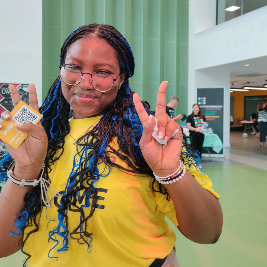A photograph of Rivia holding UWS merch
