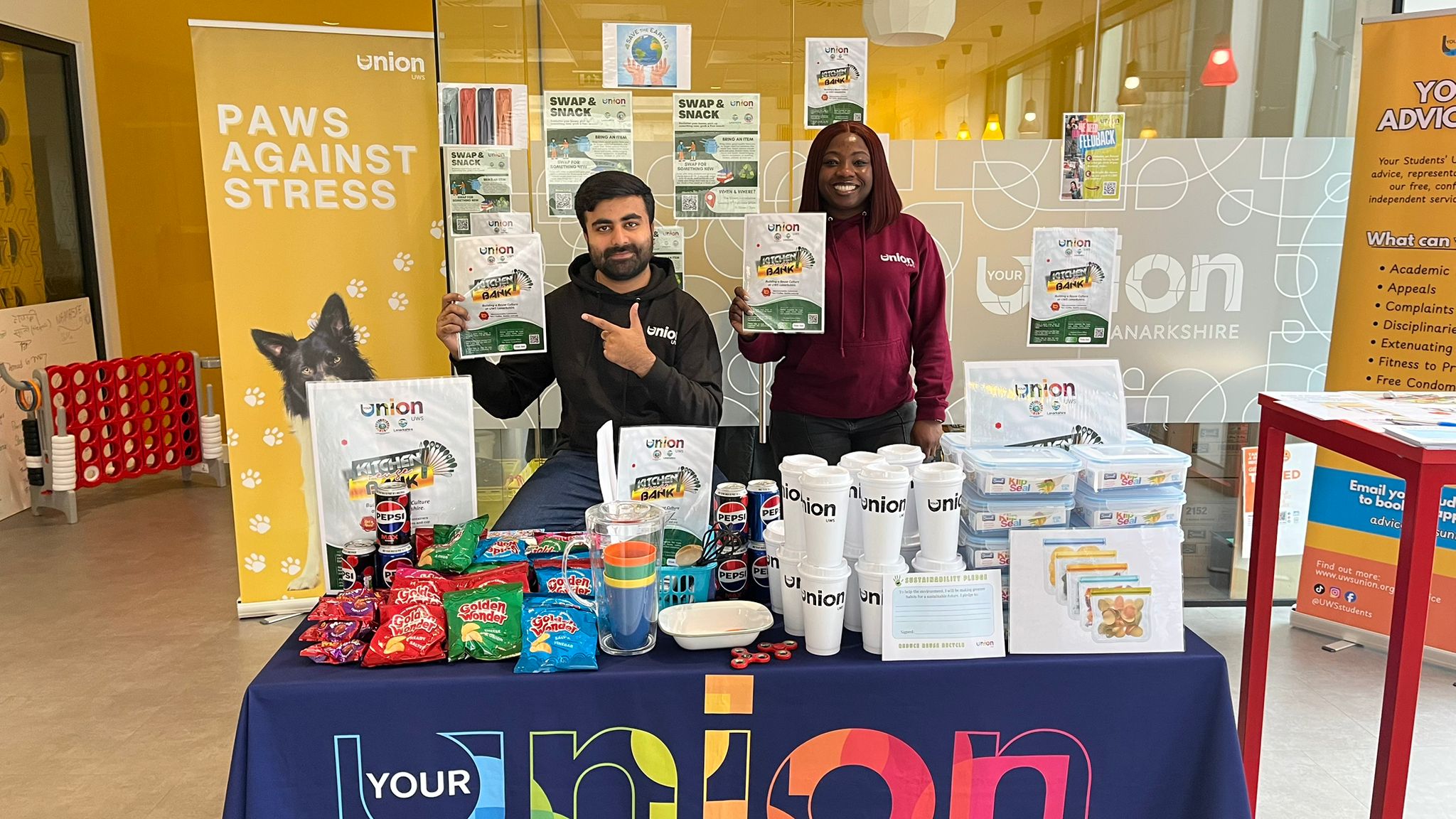 Photo of UWS Students' President Omowaleola and Vice President Shahan distributing free essentials like microwavable storage containers and reusable cups.